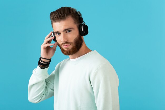 Retrato de um jovem barbudo elegante e atraente ouvindo música em fones de ouvido sem fio estilo moderno humor confiante