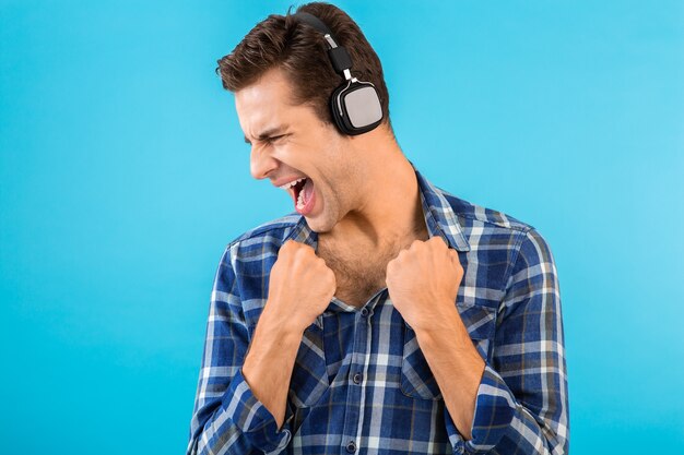 Retrato de um jovem bonito elegante e atraente ouvindo música em fones de ouvido sem fio, se divertindo em estilo moderno e feliz humor emocional