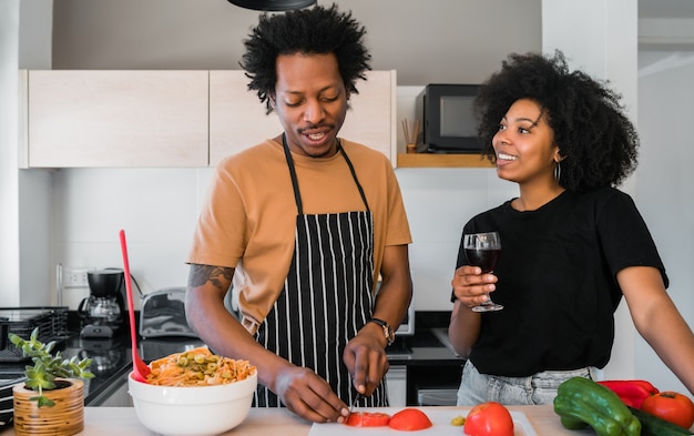Retrato de um jovem casal afro cozinhando juntos na cozinha em casa. Conceito de relacionamento, cozinheiro e estilo de vida.