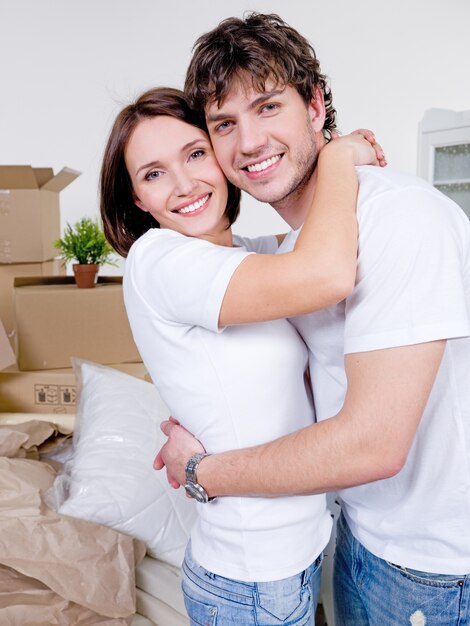 Retrato de um jovem casal apaixonado e alegre com um sorriso feliz na nova casa