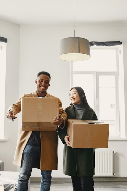 Retrato de um jovem casal com caixas de papelão na nova casa, conceito de casa em movimento.