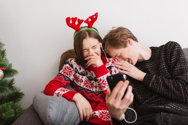 Retrato de um jovem casal feliz sentado no sofá em casa e ouvindo música enquanto passa tempo juntos