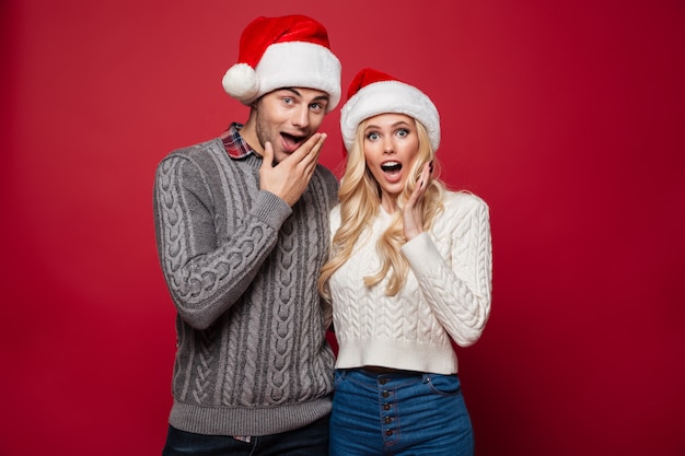 Retrato de um jovem casal surpreso em chapéus de Natal