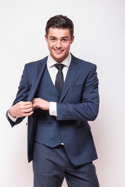 Retrato de um jovem empresário sorridente e feliz em um terno azul isolado na parede branca