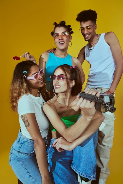 Retrato de um jovem grupo de amigos no estilo de moda dos anos 2000 posando com câmera