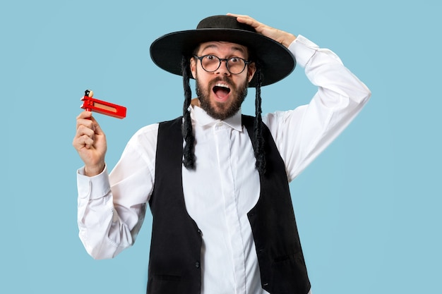 Foto grátis retrato de um jovem judeu ortodoxo com catraca de madeira durante o festival de purim