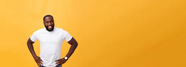 Retrato de um jovem negro moderno sorrindo em pé sobre fundo amarelo isolado