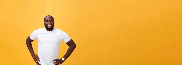 Retrato de um jovem negro moderno sorrindo em pé sobre fundo amarelo isolado