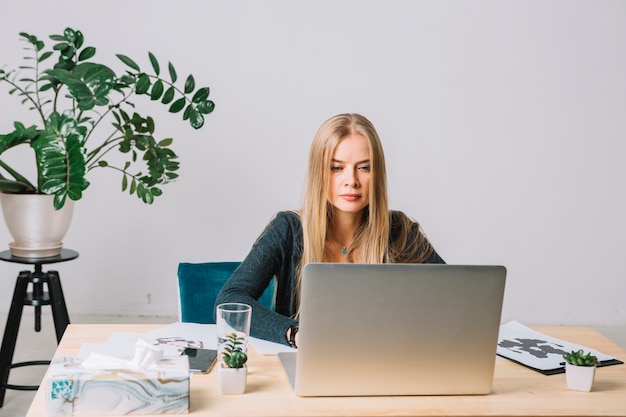 Retrato de um jovem psicólogo loira usando laptop na mesa no escritório