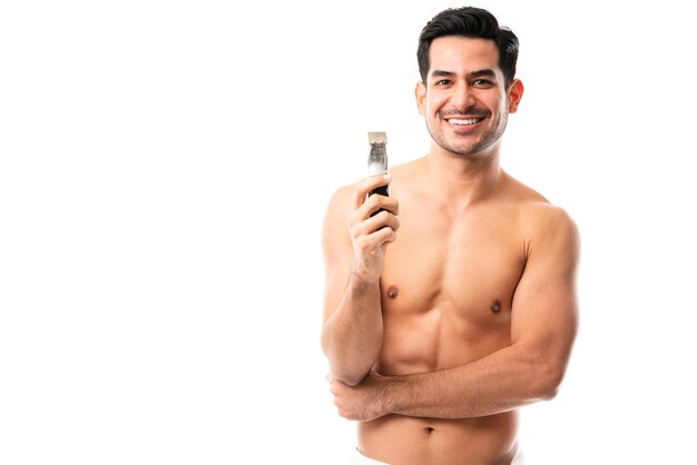 Retrato de um jovem sem camisa segurando uma navalha e fazendo contato visual contra fundo branco