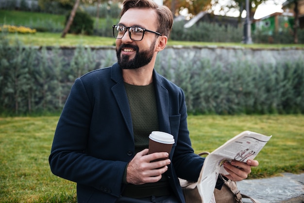 Retrato de um jovem sorridente, sentado com um jornal