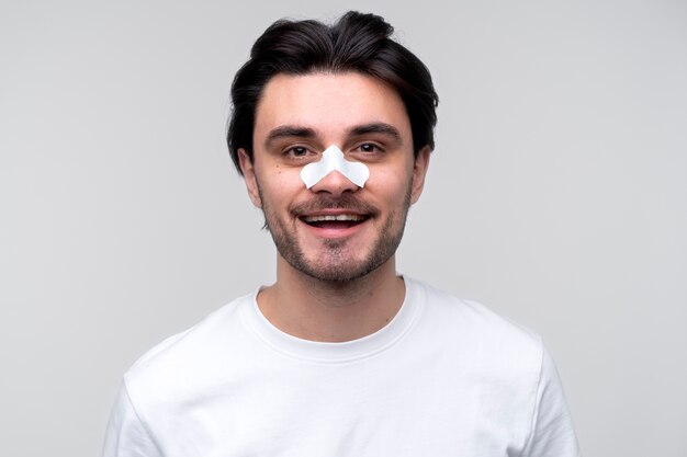 Retrato de um jovem sorrindo e usando um tapa-nariz