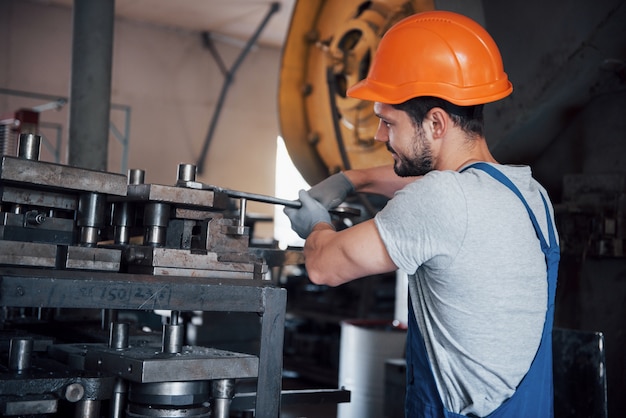 Retrato de um jovem trabalhador em um capacete em uma grande usina de metais.