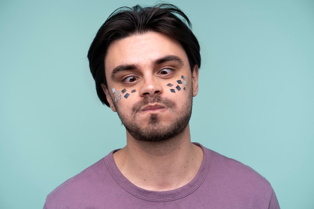 Retrato de um jovem usando confete no rosto e fazendo uma careta