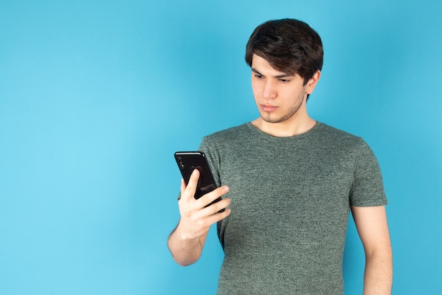 Retrato de um jovem usando um telefone celular contra o azul.