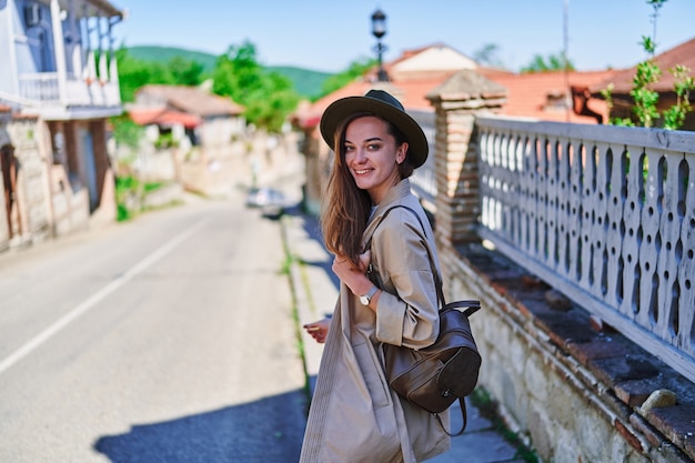 Retrato de um lindo feliz alegre atraente sorridente caminhando jovem viajante usando chapéu e mochila em um dia ensolarado Foto Premium
