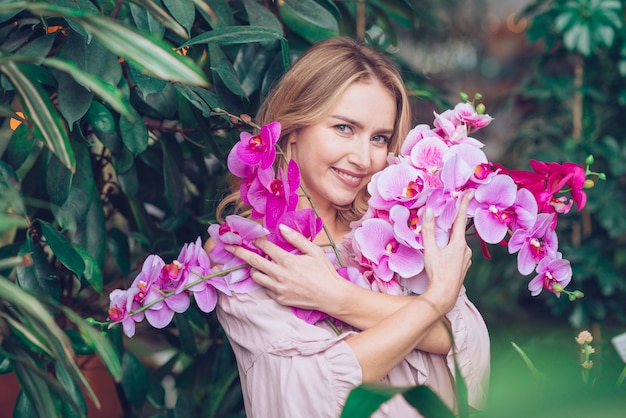 Foto grátis retrato, de, um, loiro, mulher jovem, abraçar, a, ramos, de, orquídea, flores