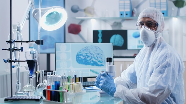 Retrato de um médico especialista com equipamento ppe, analisando amostra de DNA, trabalhando na experiência de diagnóstico de doenças durante o experimento de microbiologia no laboratório de um hospital médico. Conceito de medicina