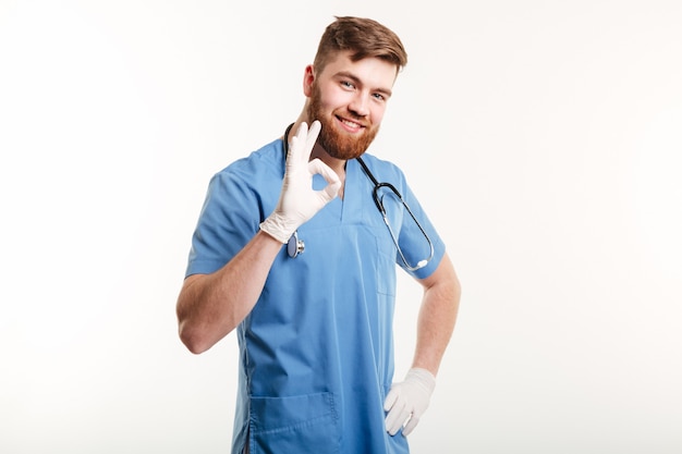 Retrato de um médico homem feliz e amigável mostrando o gesto ok