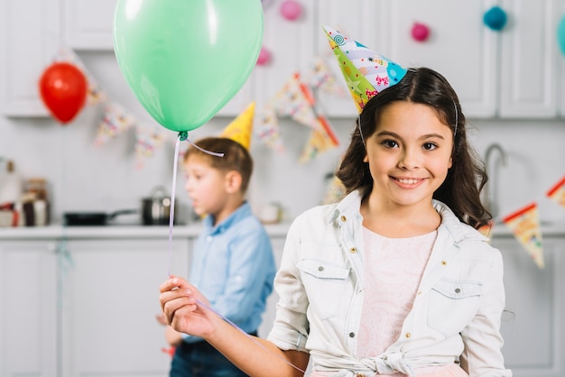 Retrato, de, um, menina feliz, segurando, balloon, com, menino, andar, em, fundo