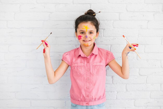 Retrato, de, um, menina, segurando, pintar escovas, em, mão, ficar, frente, parede branca tijolo