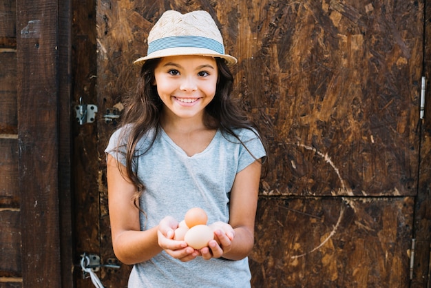 Retrato, de, um, menina sorridente, segurando, ovos, ficar, contra, rústico, parede