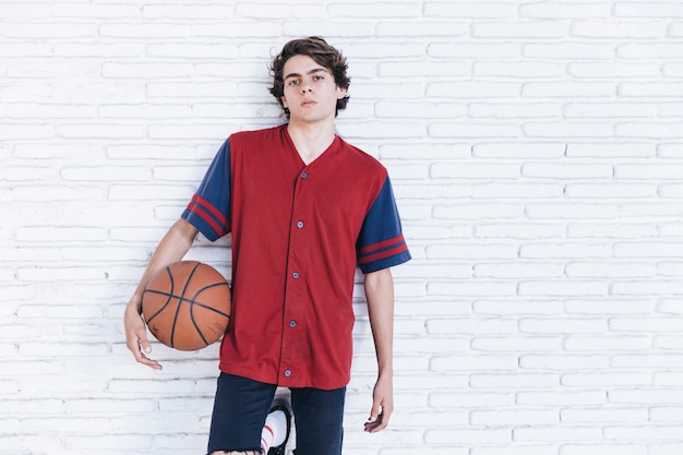 Foto grátis retrato, de, um, menino adolescente, com, basquetebol, inclinar-se, parede tijolo