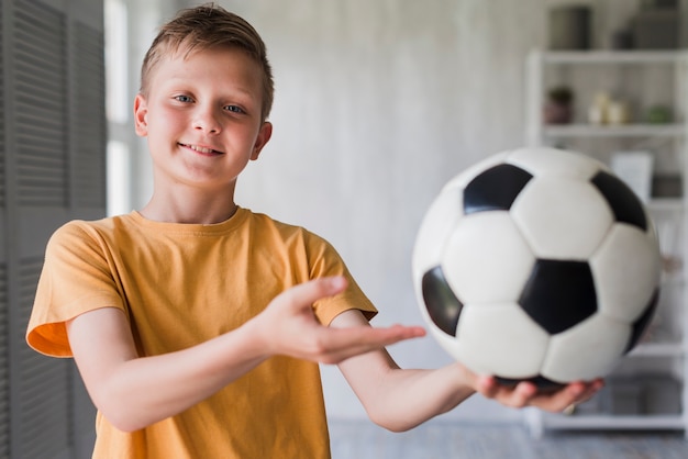 Retrato, de, um, menino sorridente, mostrando, bola futebol