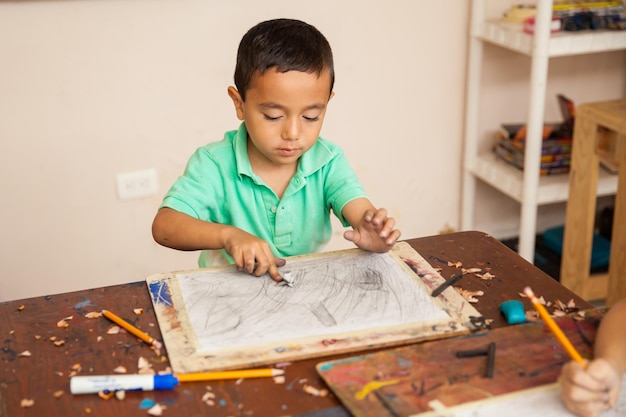 Foto grátis retrato de um menino trabalhando em um desenho para sua aula de arte na escola