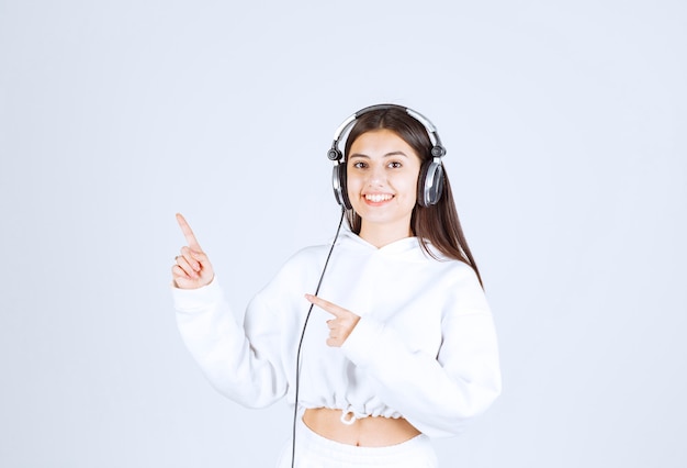 Retrato de um modelo de garota jovem e bonito com fones de ouvido aparecendo um polegar.