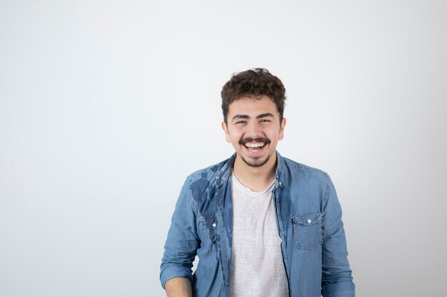 Retrato de um modelo de jovem bonito com bigode em pé e olhando para a câmera.