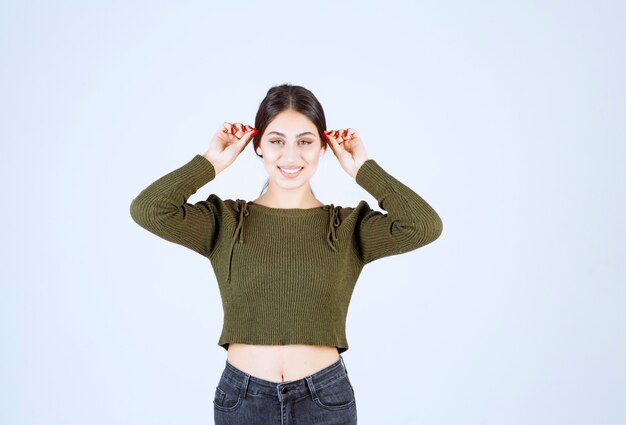 Retrato de um modelo de mulher jovem e bonita em pé e posando sobre uma parede branca.