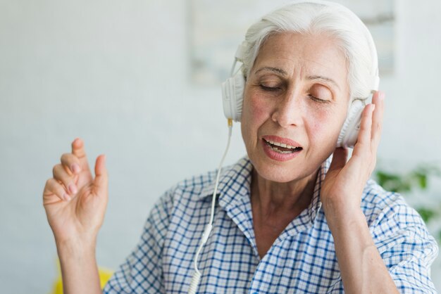 Retrato, de, um, mulher idosa, desfrutando, a, música, ligado, headphone