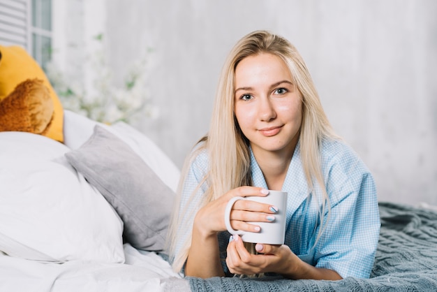 Retrato, de, um, mulher jovem, com, xícara café, mentindo cama