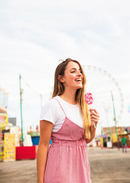 Retrato, de, um, mulher jovem, segurando, grande, pirulito, em, parque divertimento