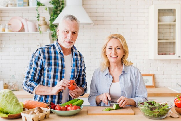 Retrato, de, um, par velho, preparar, a, alimento, olhando câmera, em, a, modernos, cozinha