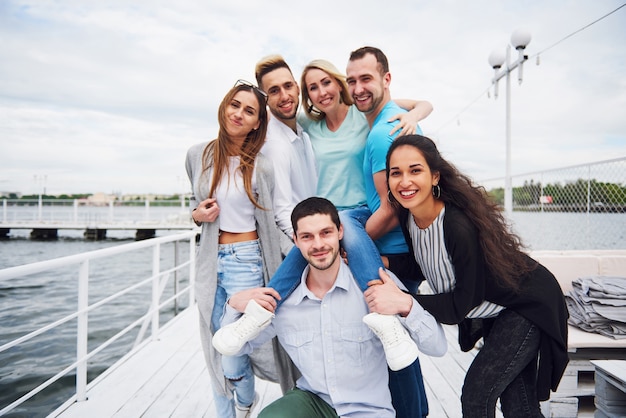 Retrato de um povo jovem e feliz em repouso no cais. Amigos desfrutando de um jogo no lago. Emoções positivas.