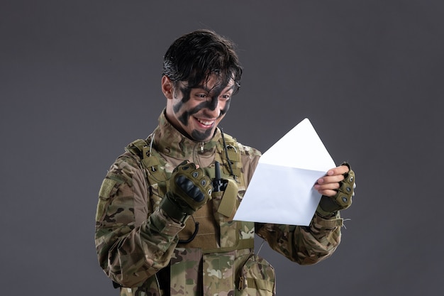 Foto grátis retrato de um soldado camuflado segurando uma carta na superfície escura