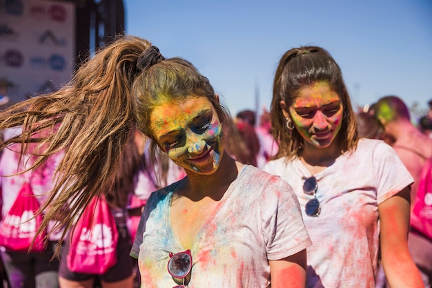 Retrato, de, um, sorrindo, dois, amigo feminino, coberto, seu, rosto, com, holi, cor