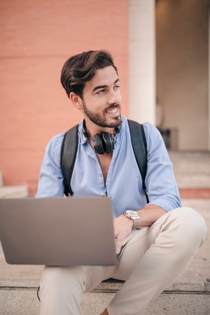 Retrato, de, um, sorrindo, homem bonito, com, laptop, olhando