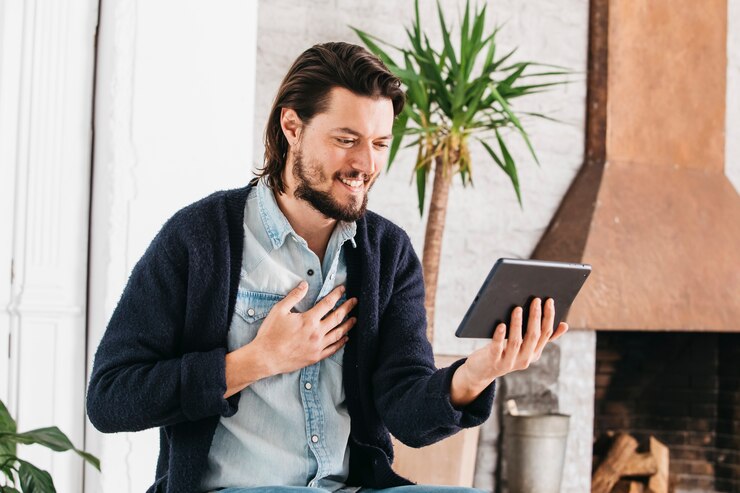 Foto grátis retrato, de, um, sorrindo, homem jovem, fazendo, chamada vídeo, usando, tablete digital