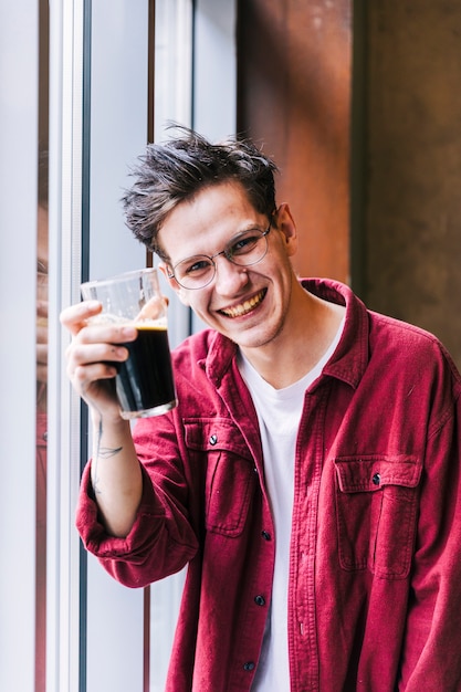 Foto grátis retrato, de, um, sorrindo, homem jovem, mostrando, a, vidro cerveja, em, câmera