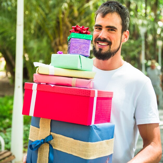 Retrato, de, um, sorrindo, homem jovem, segurando, pilha presentes