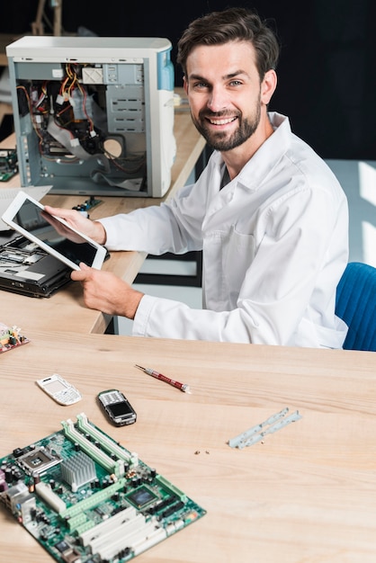 Foto grátis retrato, de, um, sorrindo, jovem, macho, técnico, segurando, tablete digital