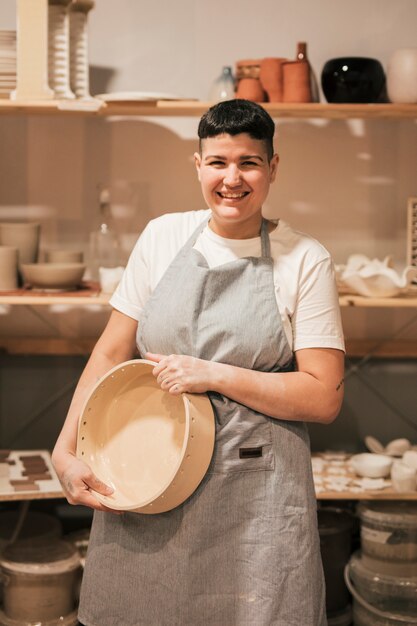 Retrato, de, um, sorrindo, mulher jovem, segurando, cerâmico, recipiente, em, mão