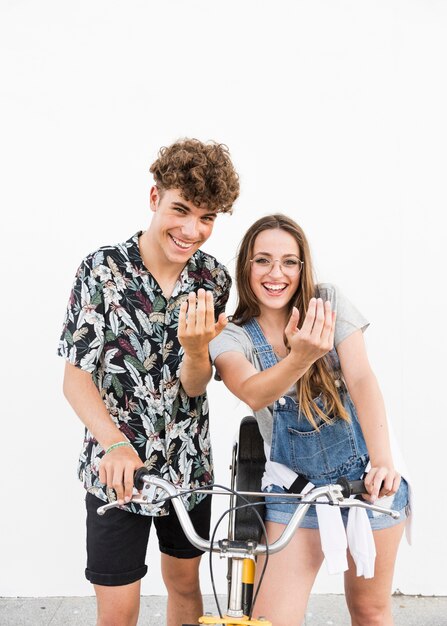 Retrato, de, um, sorrindo, par jovem, com, bicicleta, fazer, gesto mão