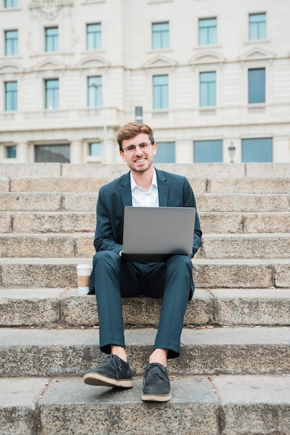 Retrato, de, um, sucedido, jovem, homem negócios, sentar escada, com, laptop