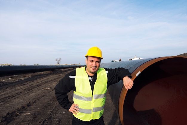 Retrato de um trabalhador industrial parado perto da tubulação de gás no canteiro de obras