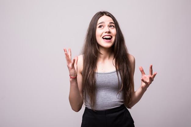 Retrato de uma adolescente alegre e feliz, vestida com uma jaqueta jeans, comemorando o sucesso enquanto dança isolada