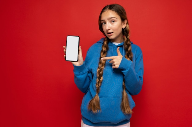 Foto grátis retrato de uma adolescente mostrando seu smartphone